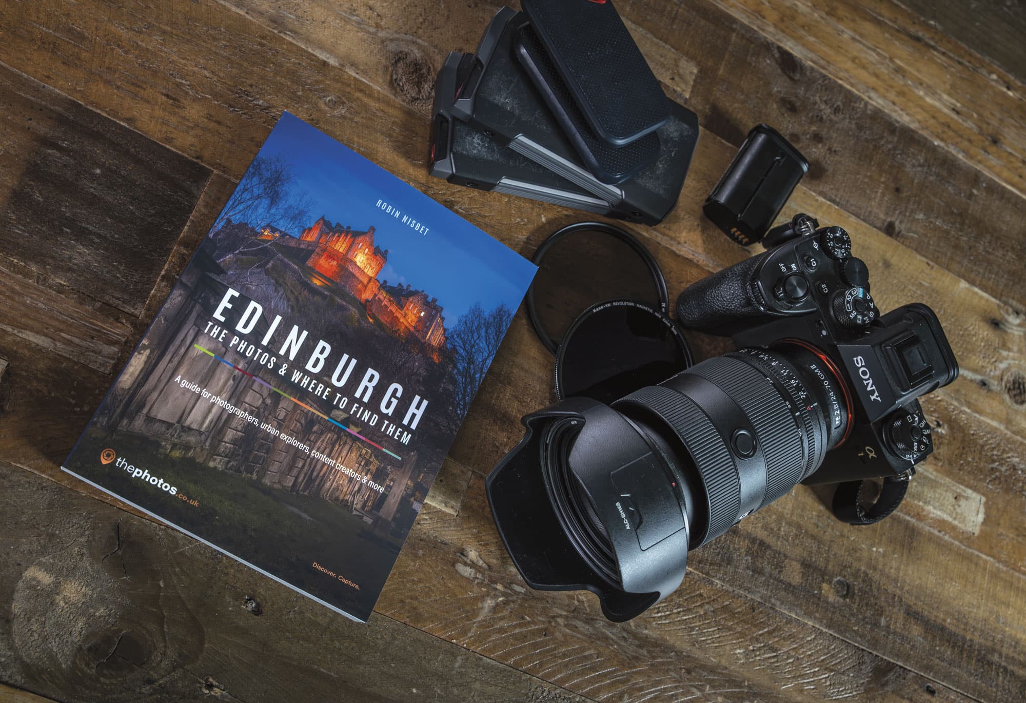 Edinburgh: The Photos & Where to Find Them auf einem Holztisch neben Kamera, Objektiv und Filtern